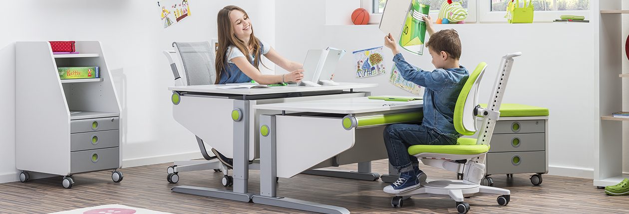 moll kids Winner comfort kinderschreibtisch_ 02_verschiedene Größen moll kids Winner comfort kinderschreibtisch Maximo Kinderdrehstuhl älteres Mädchen und kleiner Junge an unterschiedlich hohen Kinderschreibtischen