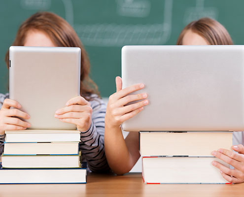 zwei schülerinnen lesen mit laptop und tablet-pc